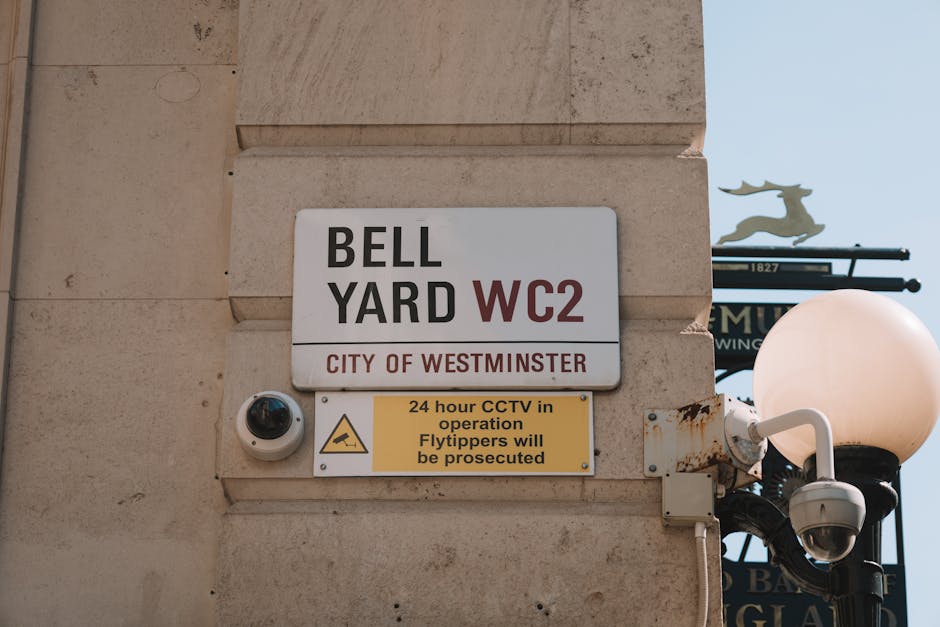 Close-up view of the facade of a building at High Holborn in Aldwych, showing a white rectangular street sign with black and red text reading 'High Holborn WC1' mounted on a cream-colored stone wall w